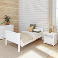 Cozy neutral modern farmhouse bedroom with white shiplap wall, white bed and dresser, beige layered bedding, woven jute rug, potted plants and wooden table lamp