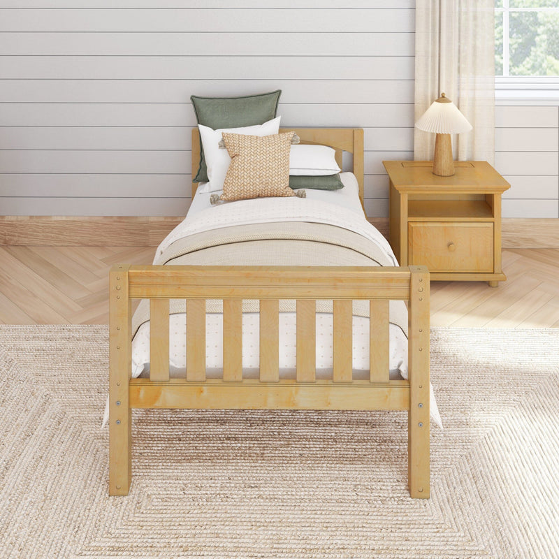 Farmhouse bedroom with wooden single bed, neutral bedding, knitted throw pillow, wooden nightstand and lamp against a white shiplap wall