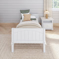 Neutral farmhouse bedroom: white twin bed with woven and green pillows, beige layered bedding, white nightstand, wood pleated lamp and shiplap wall