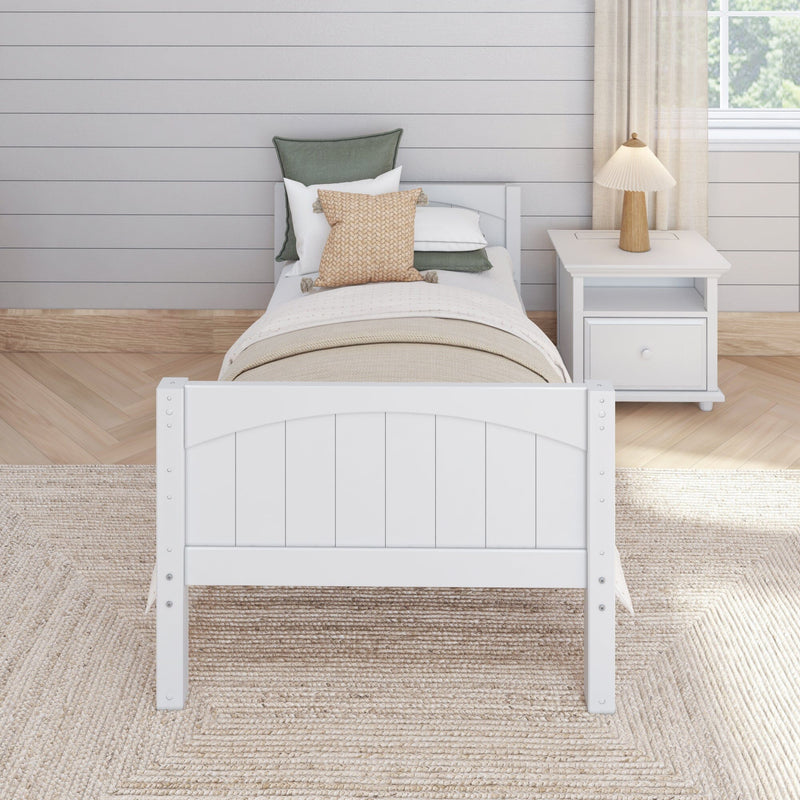Neutral farmhouse bedroom: white twin bed with woven and green pillows, beige layered bedding, white nightstand, wood pleated lamp and shiplap wall