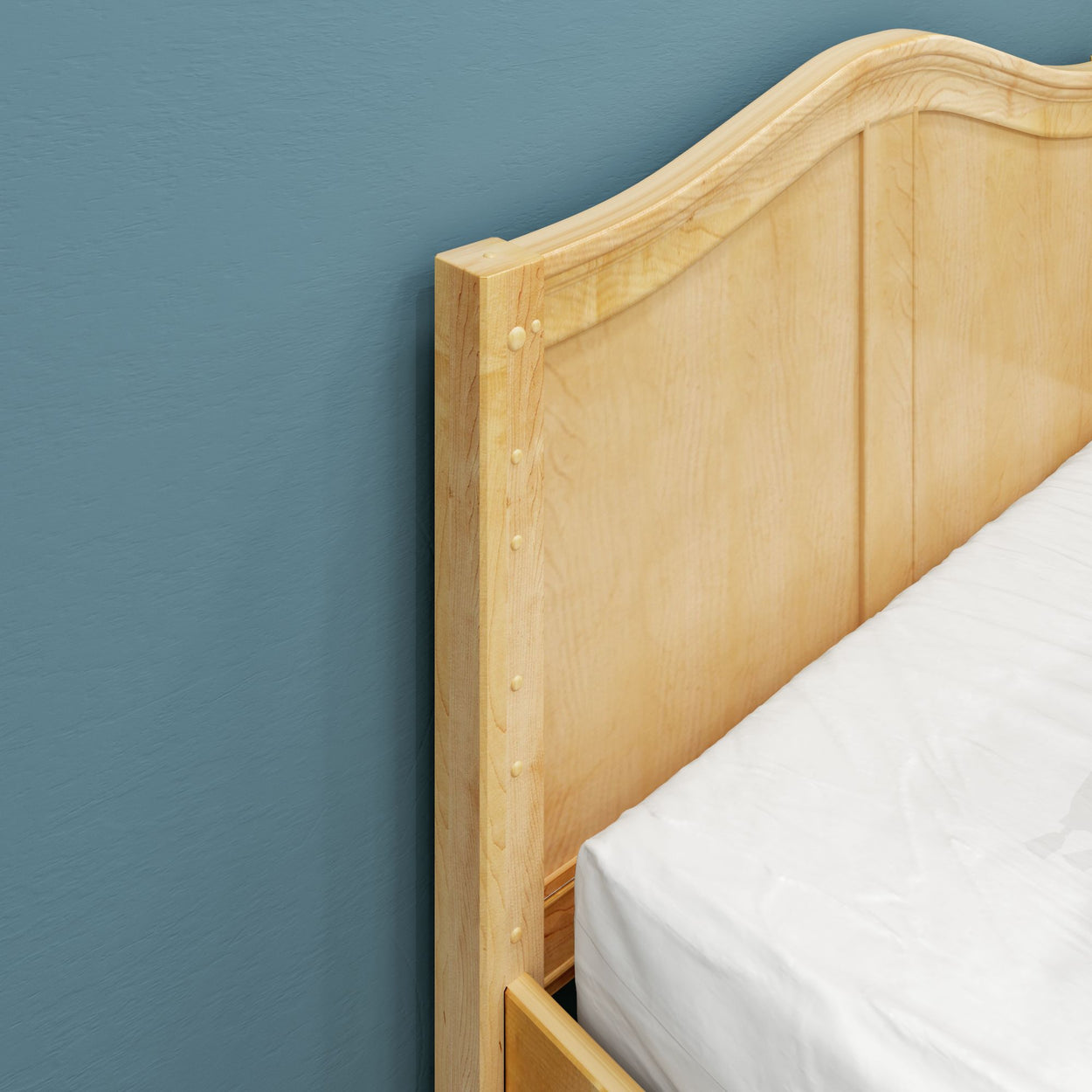 Light wood bed headboard against blue wall.