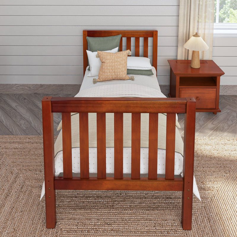 Twin wooden bed with green and beige decorative pillows and white bedding, wood nightstand with lamp, shiplap wall and jute rug, farmhouse bedroom decor