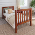 Solid wood twin bed with slatted headboard and neutral textured bedding in a cozy farmhouse bedroom with woven jute rug, potted fiddle leaf fig, window and soft natural light