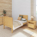 Cozy bedroom with light wood bed, neutral decor, white shiplap wall, woven rug, bedside lamp and potted plants