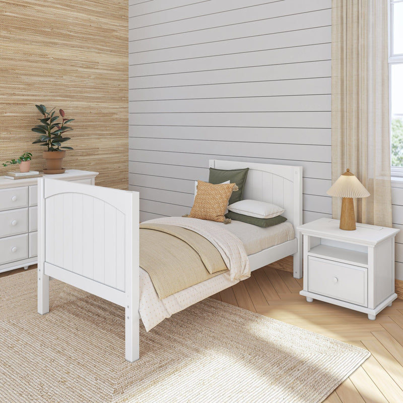 Cozy neutral bedroom with white twin bed, beige layered bedding, woven rug, shiplap accent wall, potted plants and natural wood lamp
