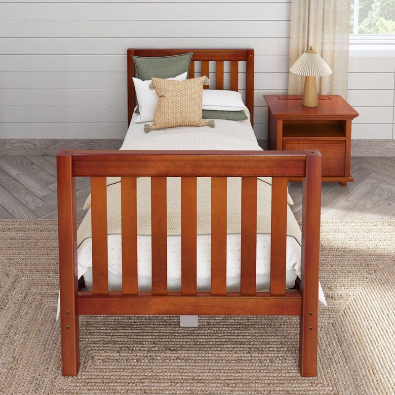 Twin wooden bed with slatted headboard and footboard, layered neutral bedding and woven tassel throw pillow, wooden nightstand with pleated lamp, shiplap wall and jute rug in a cozy modern farmhouse bedroom