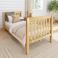 Cozy farmhouse bedroom with natural wooden bed frame, neutral bedding and knit pillows, woven jute rug, shiplap wall and bedside lamp