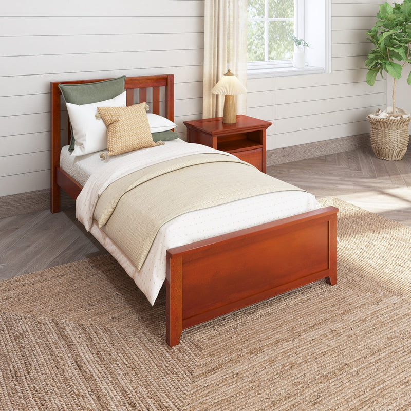 Cozy sunlit bedroom with reddish wooden twin bed, neutral layered bedding and textured pillows, matching nightstand with lamp, shiplap walls, potted plant, and natural jute rug