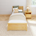 Cozy minimalist farmhouse twin bedroom with natural wood bed and nightstand, beige bedding, woven accent pillows, pleated lamp, shiplap wall, and light hardwood floor