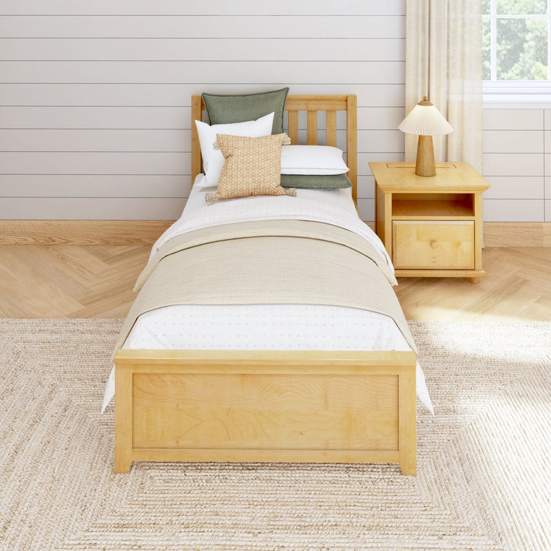 Neutral farmhouse bedroom with wooden single bed, beige and white layered bedding, woven cushion, wooden nightstand and lamp against a shiplap wall