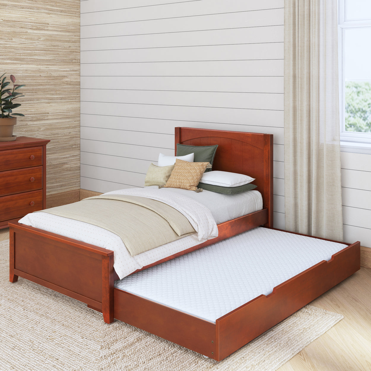 Wooden twin bed with pull-out trundle and bedding in modern bedroom.