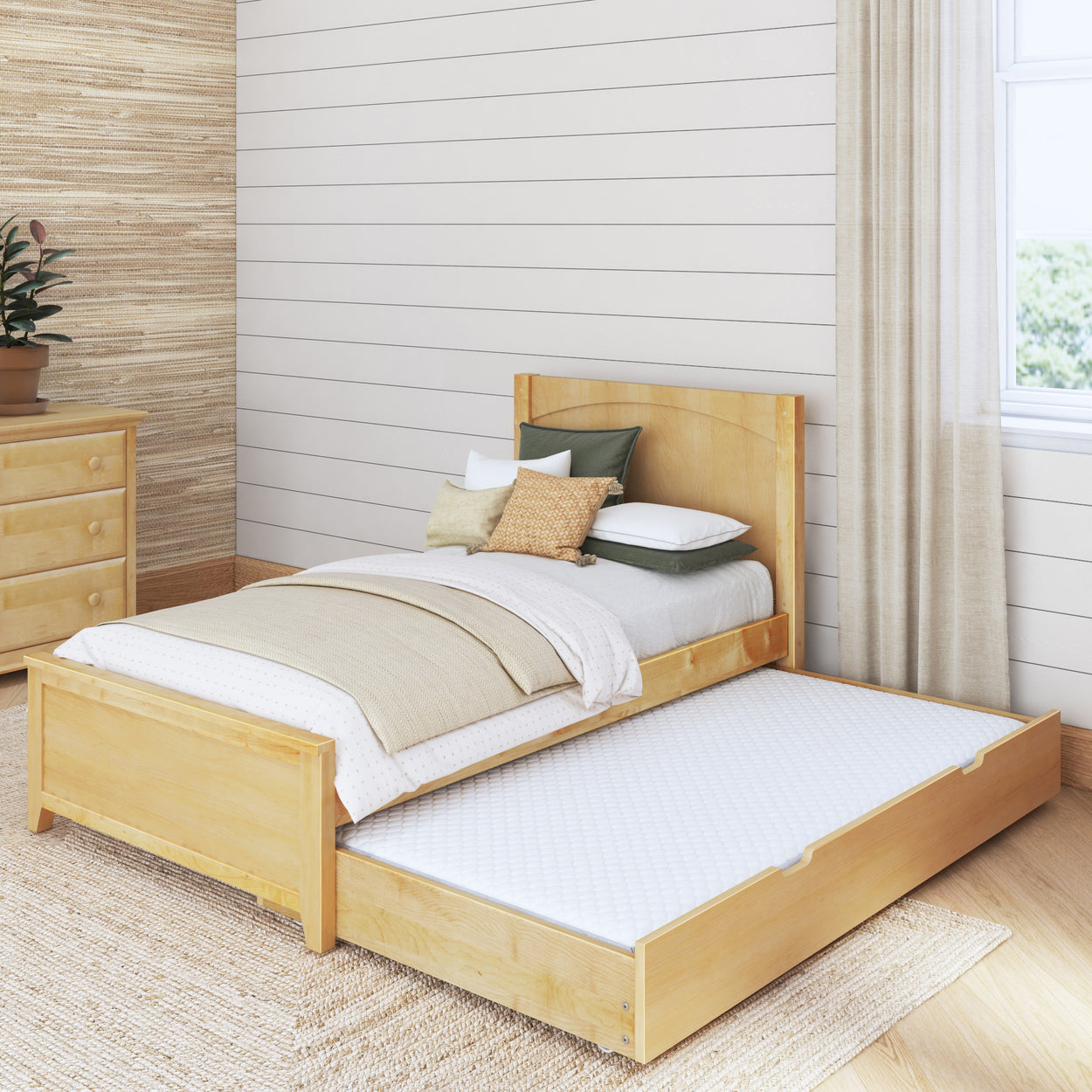 Wooden trundle bed with bedding in cozy bedroom with natural light.