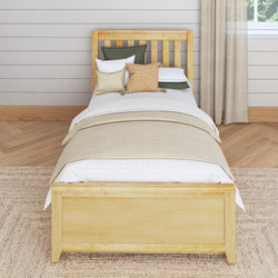 Single wooden bed with beige bedding and decorative pillows in a cozy, modern bedroom setting.