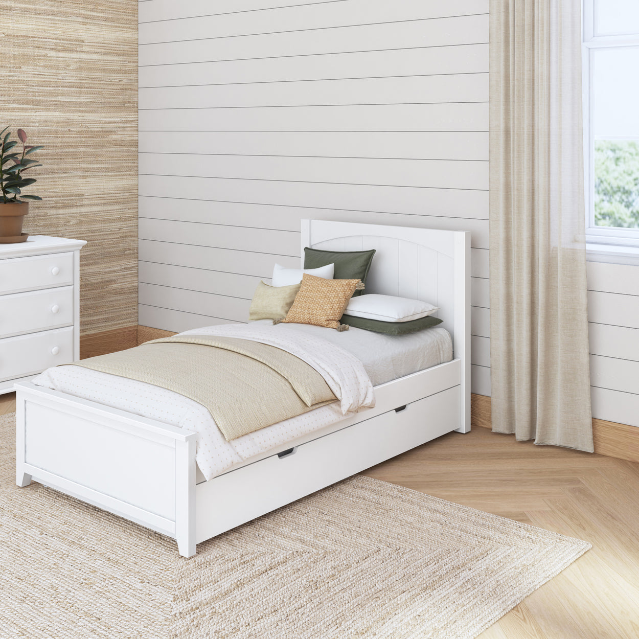 Cozy modern bedroom with white wooden bed frame, beige and green pillows, and light wood flooring.