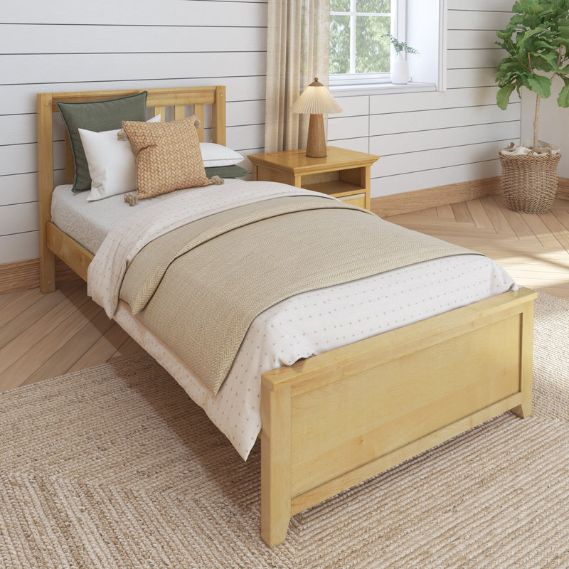 Cozy neutral farmhouse bedroom with wooden bed frame, beige layered bedding and textured throw pillows, nightstand lamp, shiplap wall, sunlit window and woven jute rug