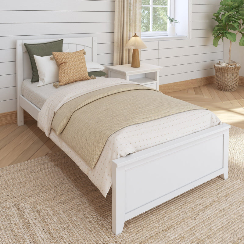 Cozy neutral farmhouse bedroom with white wooden bed, layered beige bedding and knitted pillows, bedside table with lamp, shiplap walls, jute rug and potted fiddle leaf fig