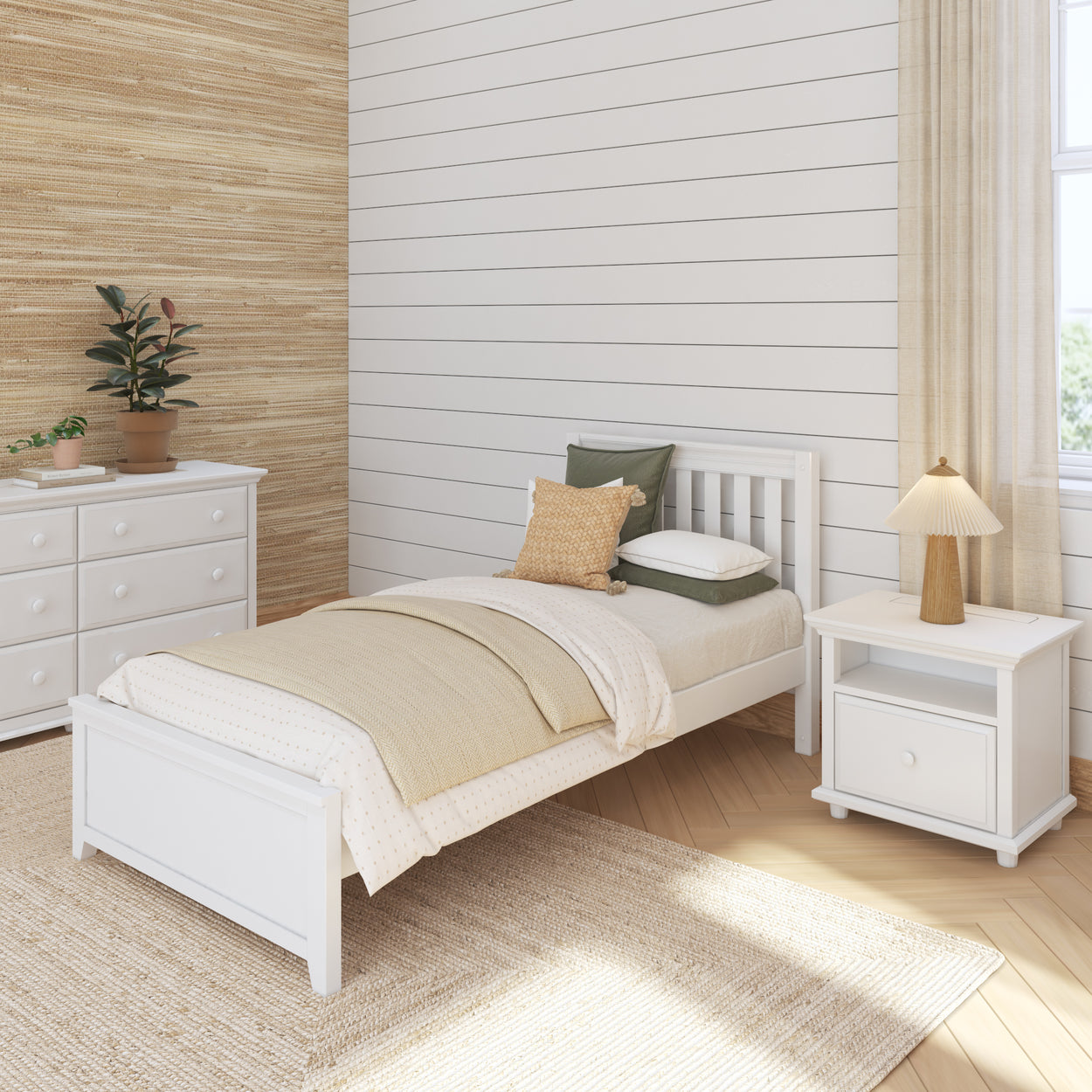 Cozy bedroom with white bed, green and beige pillows, woven rug, and potted plant decor.