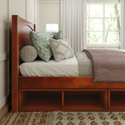 Wooden bed frame with stylish bedding and decorative pillows in a cozy bedroom setting.