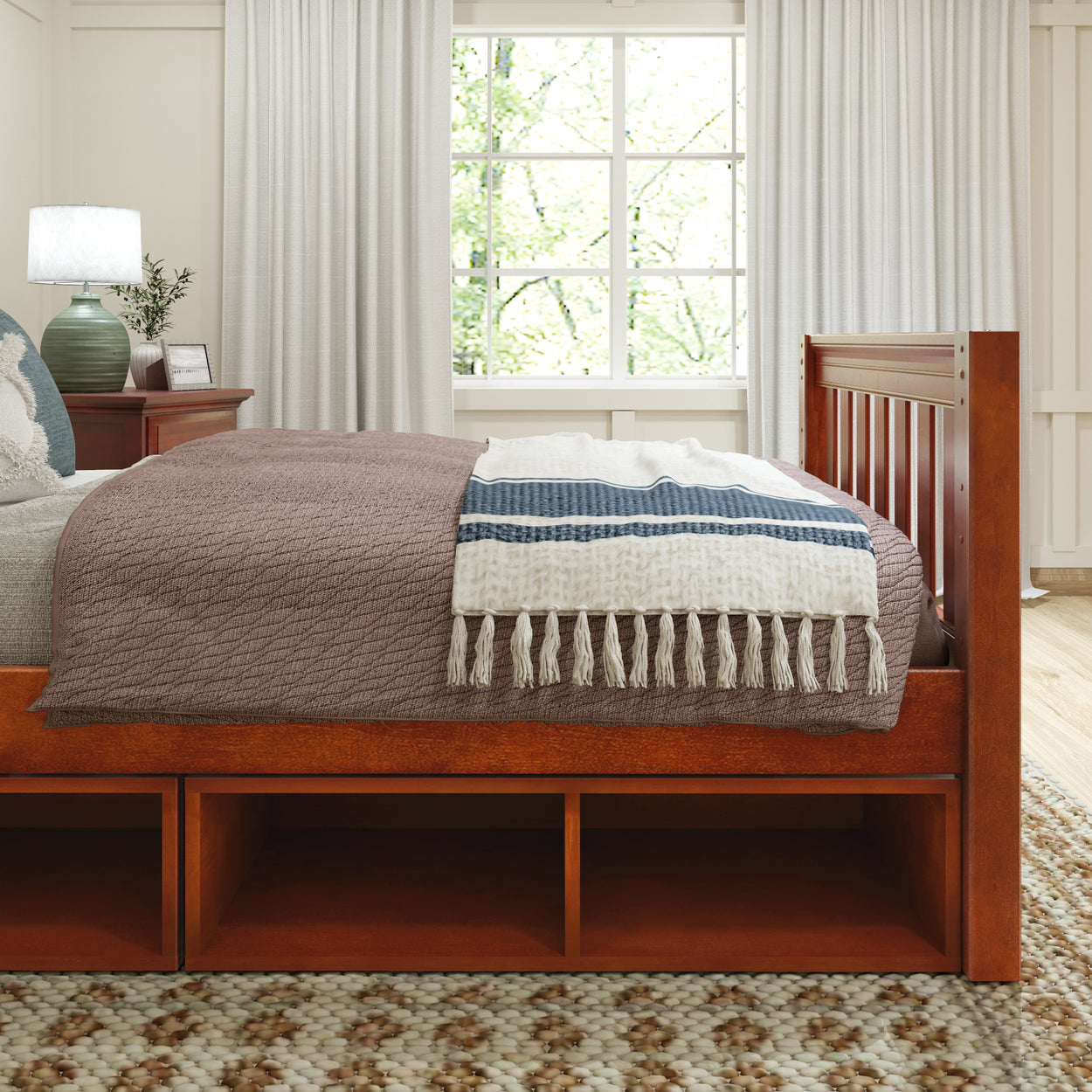 Wooden bedroom furniture set with storage, featuring a neatly made bed with a fringed blanket, positioned beside a window with natural light.