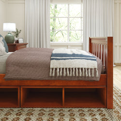 Wooden bedroom furniture set with storage, featuring a neatly made bed with a fringed blanket, positioned beside a window with natural light.