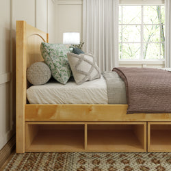 Cozy bedroom with a wooden bed frame, decorative pillows, and a soft blanket near a bright window.
