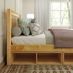 Cozy bedroom with a wooden bed frame, decorative pillows, and soft lighting near a window.