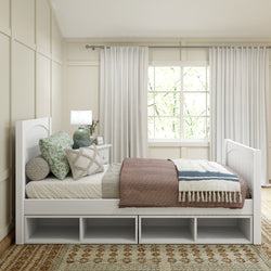 Modern bedroom with a white wooden daybed featuring storage shelves, cozy pillows, and layered bedding in neutral tones, complemented by natural light from a large window.