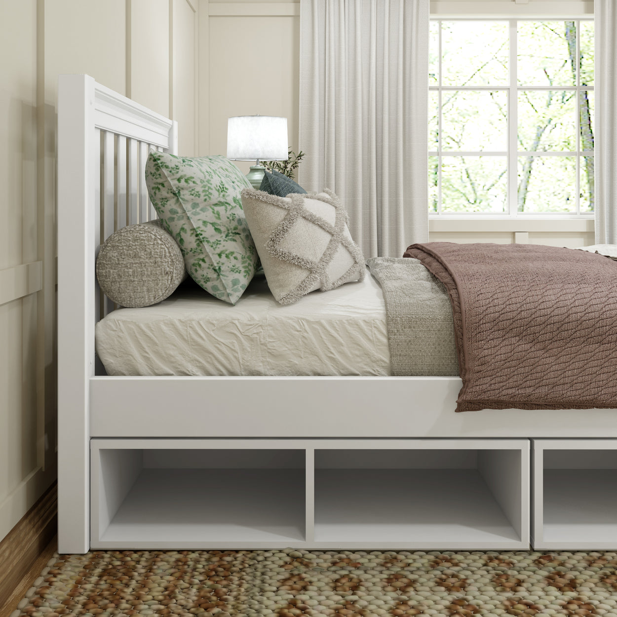 Modern bedroom with white bed frame, decorative pillows, cozy blanket, and natural lighting.