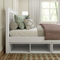 Modern bedroom with white bed frame, decorative pillows, cozy blanket, and natural lighting.
