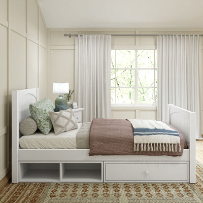 Modern bedroom with white daybed featuring storage drawers, decorative pillows, and cozy blankets next to a large window with white curtains.