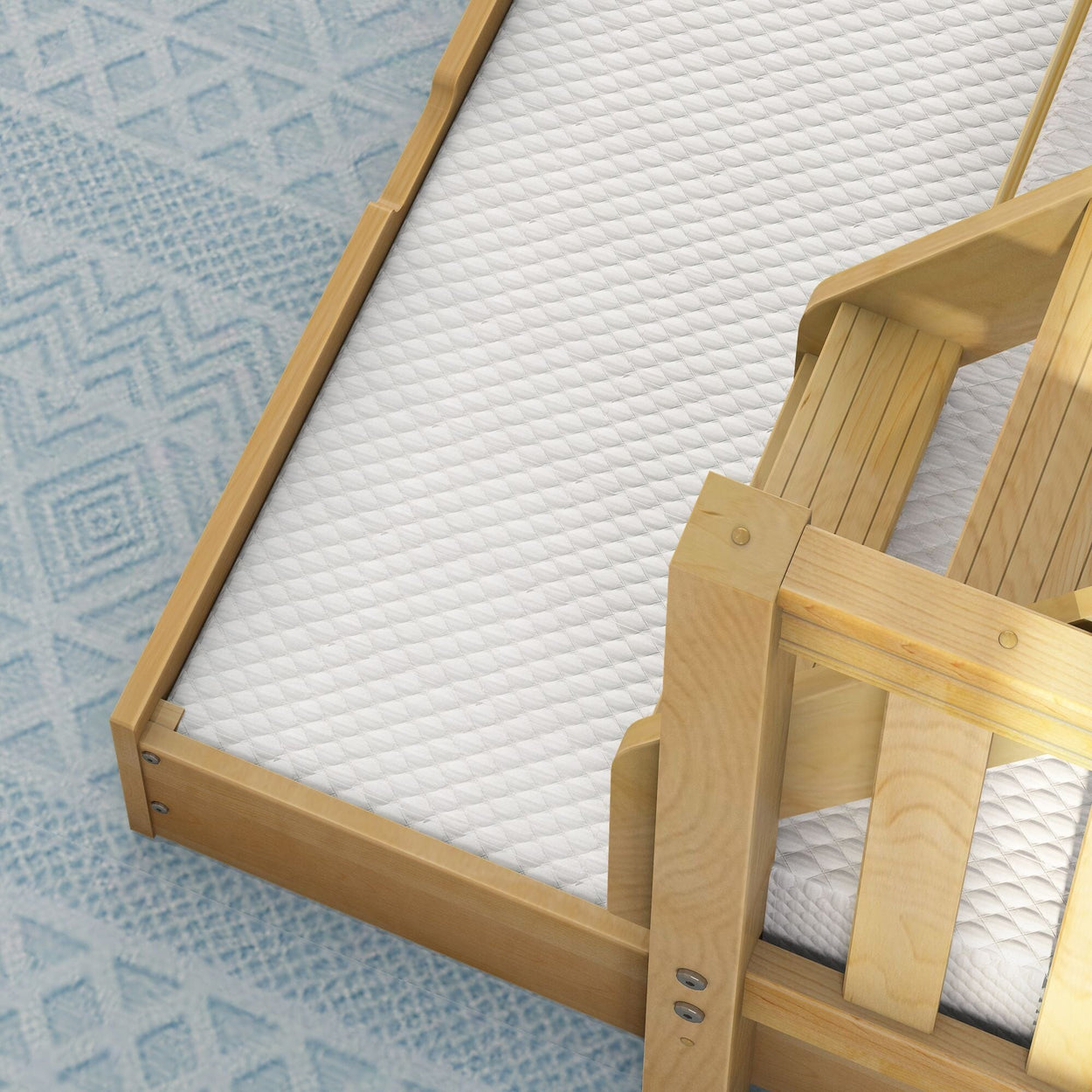 Wooden crib with a white mattress on a blue patterned rug.