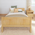 Cozy farmhouse bedroom with light wood bed frame, neutral textured bedding, decorative pillows, wooden nightstand and pleated table lamp against a white shiplap wall