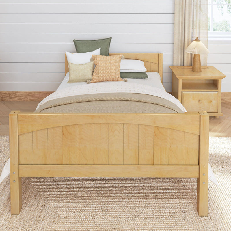 Cozy farmhouse bedroom with light wood bed frame, neutral textured bedding, decorative pillows, wooden nightstand and pleated table lamp against a white shiplap wall
