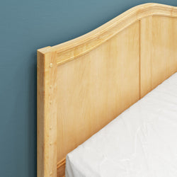 Wooden bed headboard with mattress against a teal wall.