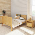 Cozy minimalist bedroom with light wood bed, neutral bedding, shiplap accent wall, woven grasscloth wallpaper, potted plants, bedside lamp, natural light