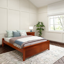 Cozy bedroom with wooden bed frame, decorative pillows, and potted plant by window.