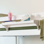 White kids bunk bed with green quilt, plush blue dinosaur toy and pink sippy cup on a bedside shelf