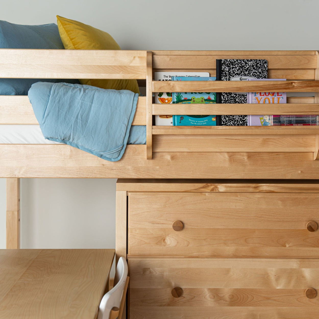 Natural maple kids' loft bed with built-in desk, drawers and bookshelf, blue quilt and yellow pillow
