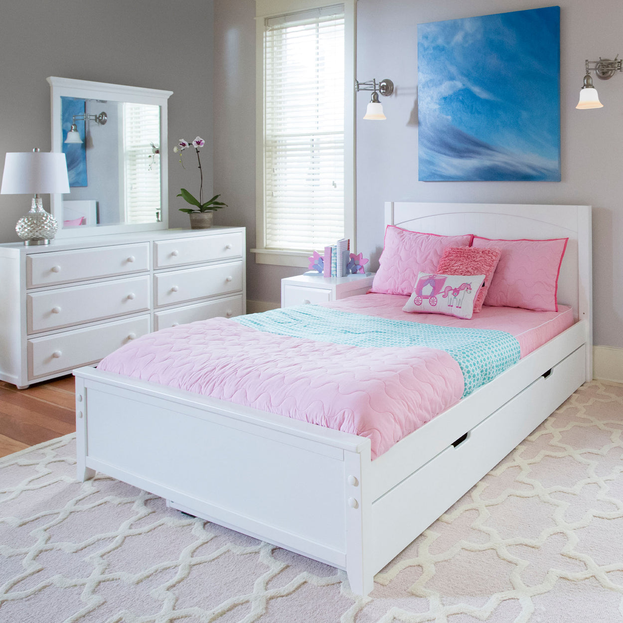 Modern children's bedroom with a white bed, pink bedding, dresser, and blue wall art.