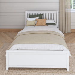 White wooden bed with cozy pillows and beige bedding in a stylish bedroom.
