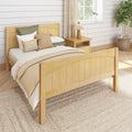 Cozy farmhouse bedroom with light wood bed and headboard, neutral layered bedding and textured pillows, wooden nightstand with lamp, shiplap wall, woven jute rug and fiddle leaf fig plant by a sunlit window