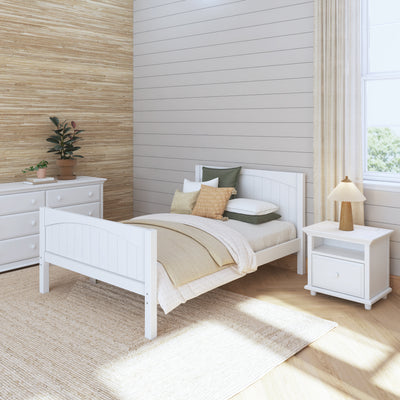Cozy bedroom interior with white wooden bed, matching nightstand, green and beige pillows, and natural light.
