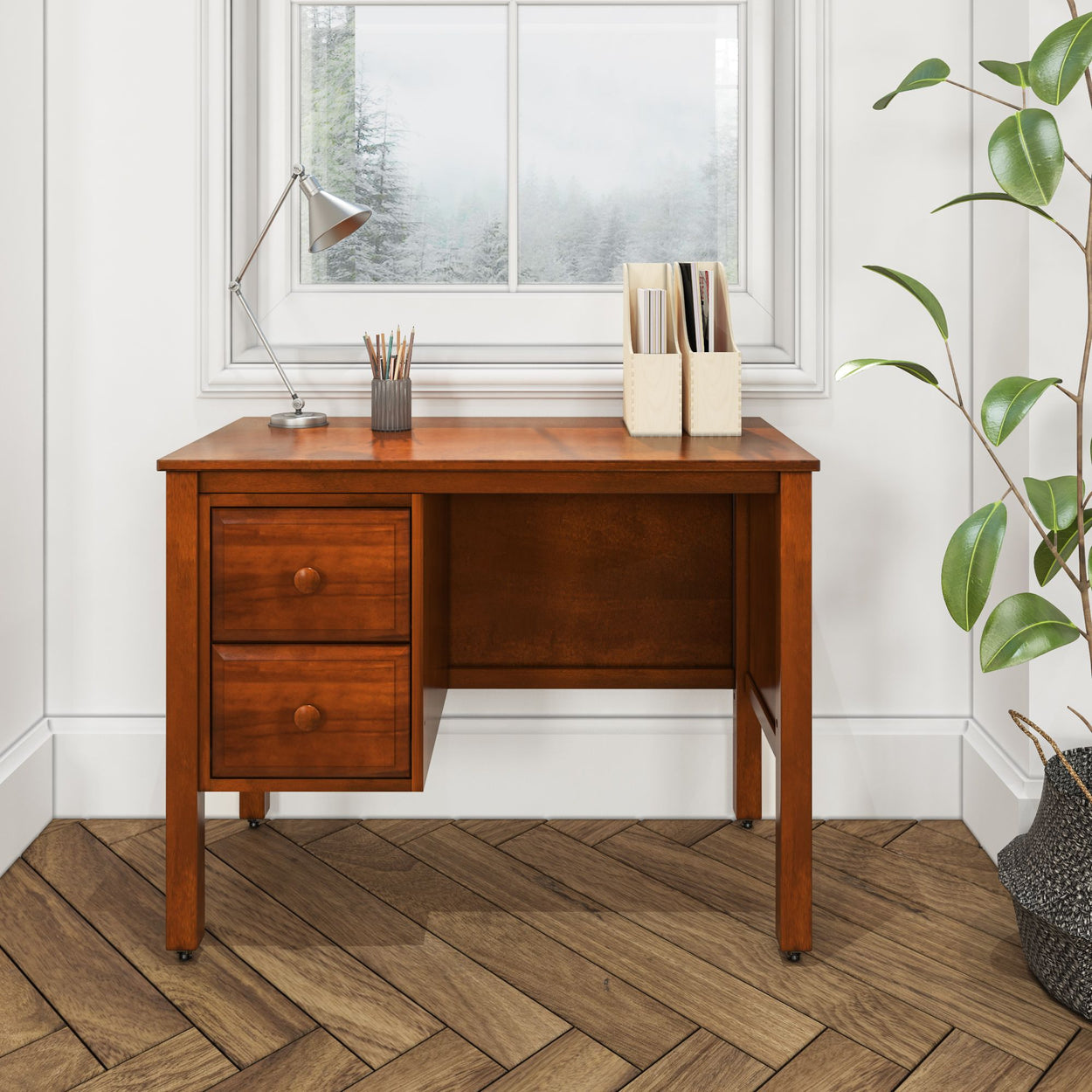 Wooden home office desk with drawers, modern lamp, and a plant in a bright room with patterned flooring.