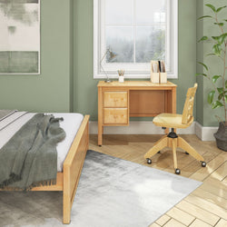 Modern bedroom with wooden desk, ergonomic chair, and green walls, featuring natural light and cozy decor.