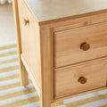 Close-up of light maple solid wood dresser drawers with round wooden knobs and natural finish on a modern Scandinavian bedroom nightstand