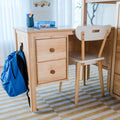 Wooden kids study desk and chair with blue backpack, pens and crayons on tabletop in an organized home learning space