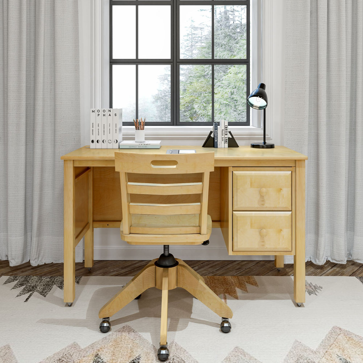 Wooden study desk with chair, books, and lamp near a window in a home office setup.
