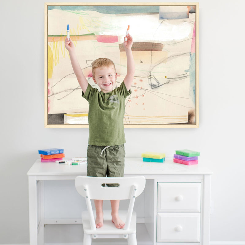 Child standing on chair drawing at white desk with colorful markers and abstract art on wall.