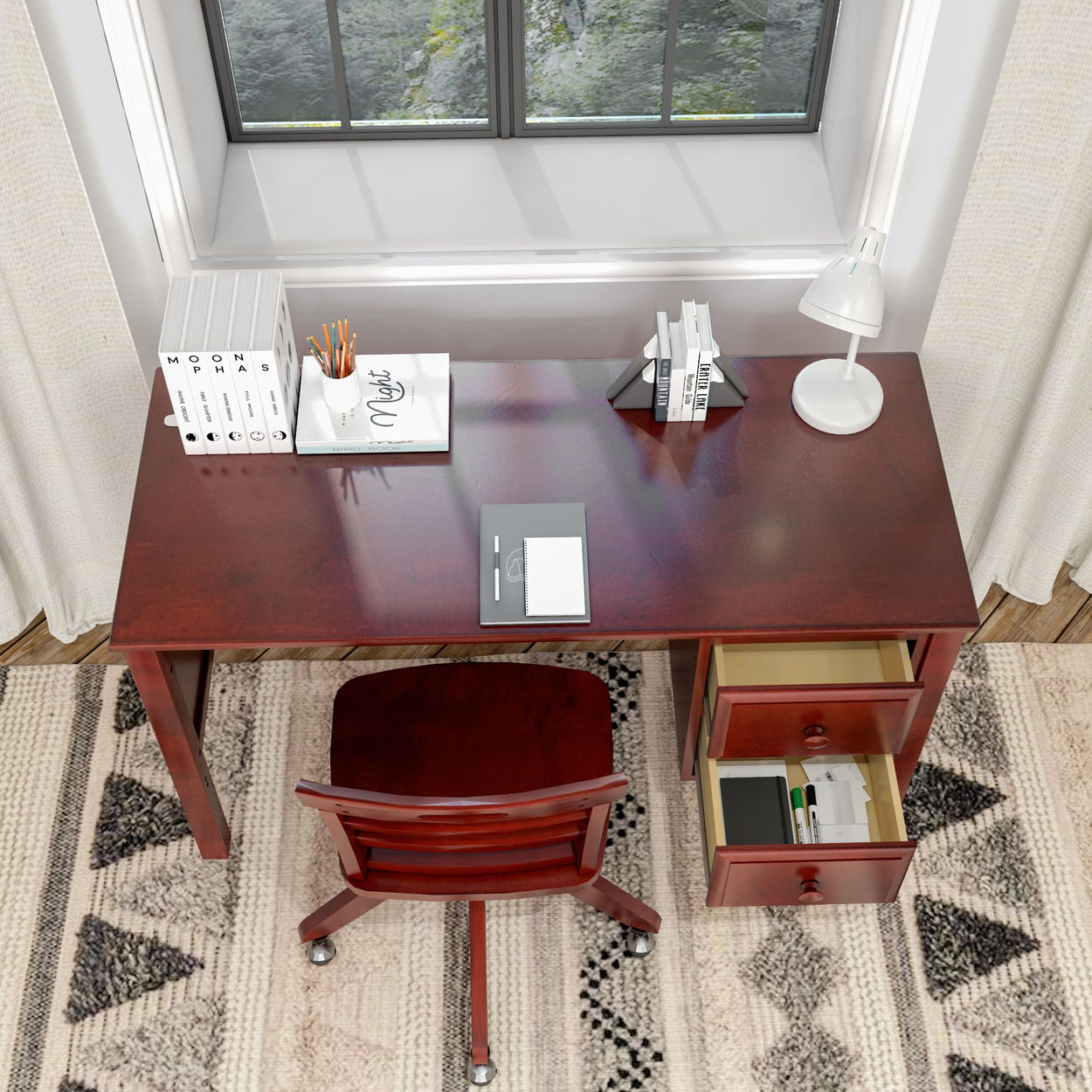 Wooden office desk with drawers, chair, and stationary items near a window.