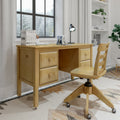 Maple wood home office desk and matching swivel chair in minimalist study nook with lamp, books, potted plant and snowy window view